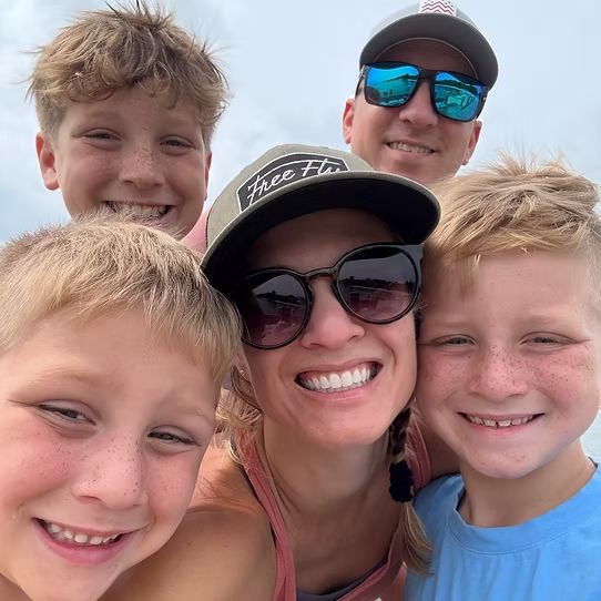 Mandi Kane on a beach day with her partner and three sons, everyone smiling for a selfie
