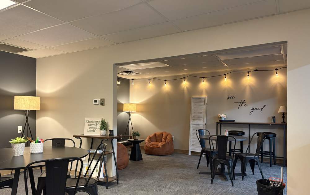 A wide view of the EmpowerED Students workspace: study tables, warm lamps, string lights, and a cozy lounge corner